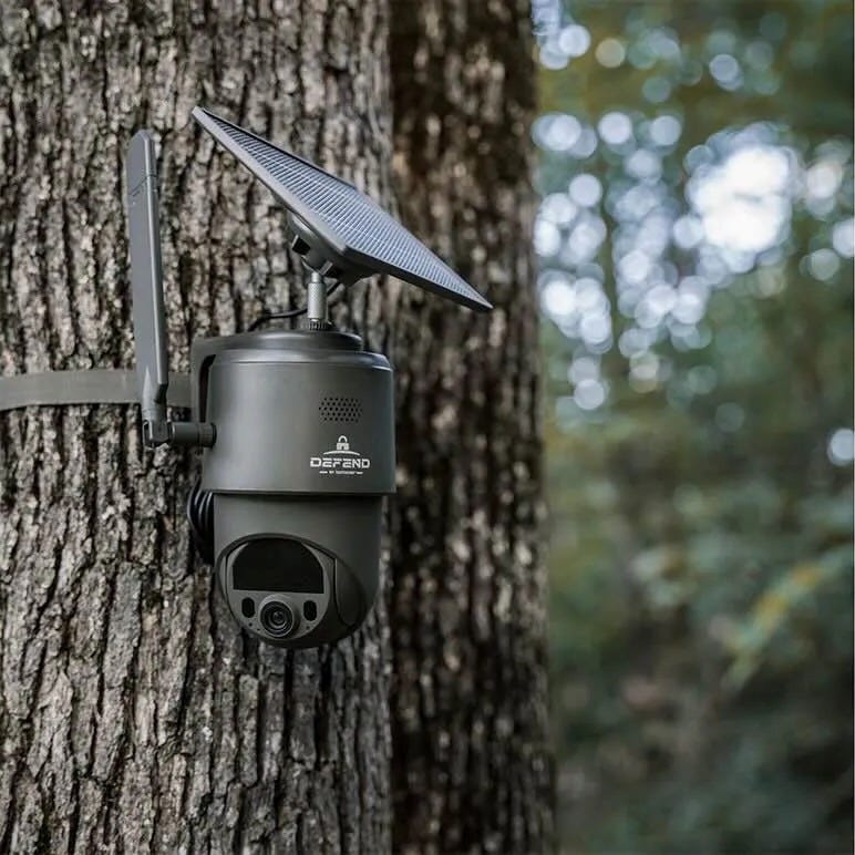 A DEFEND 360 cellular security camera with attached solar panel is mounted to a tree trunk for remote property monitoring.