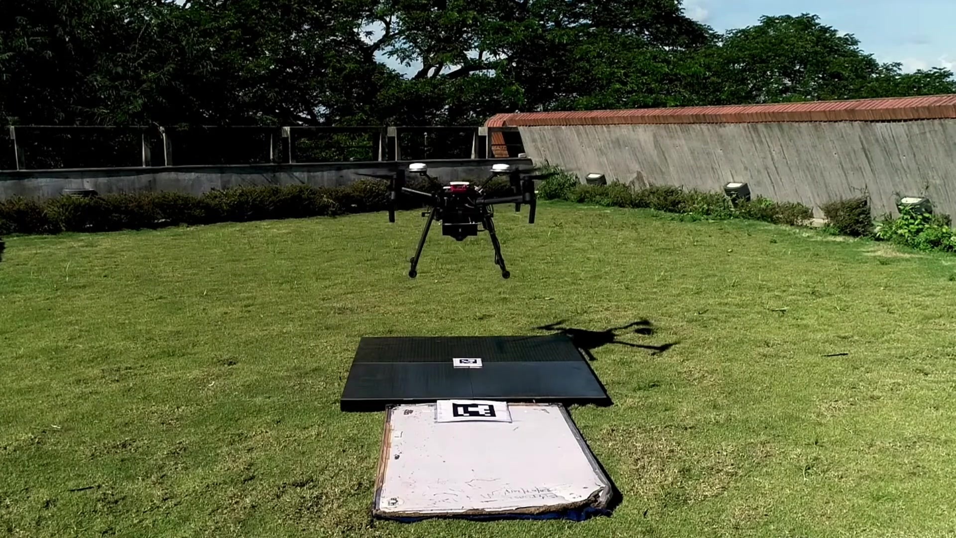 Drone descending toward a marked charging pad in a physical FlytBase precision-landing demonstration